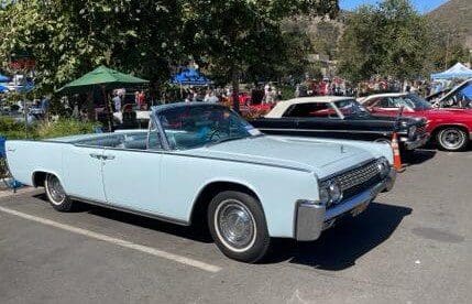 Classic light blue convertible car parked at an outdoor event.