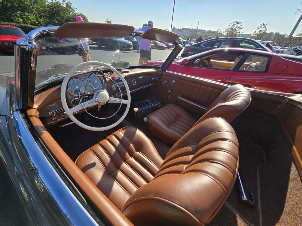 Classic car interior with brown leather seats and vintage steering wheel.