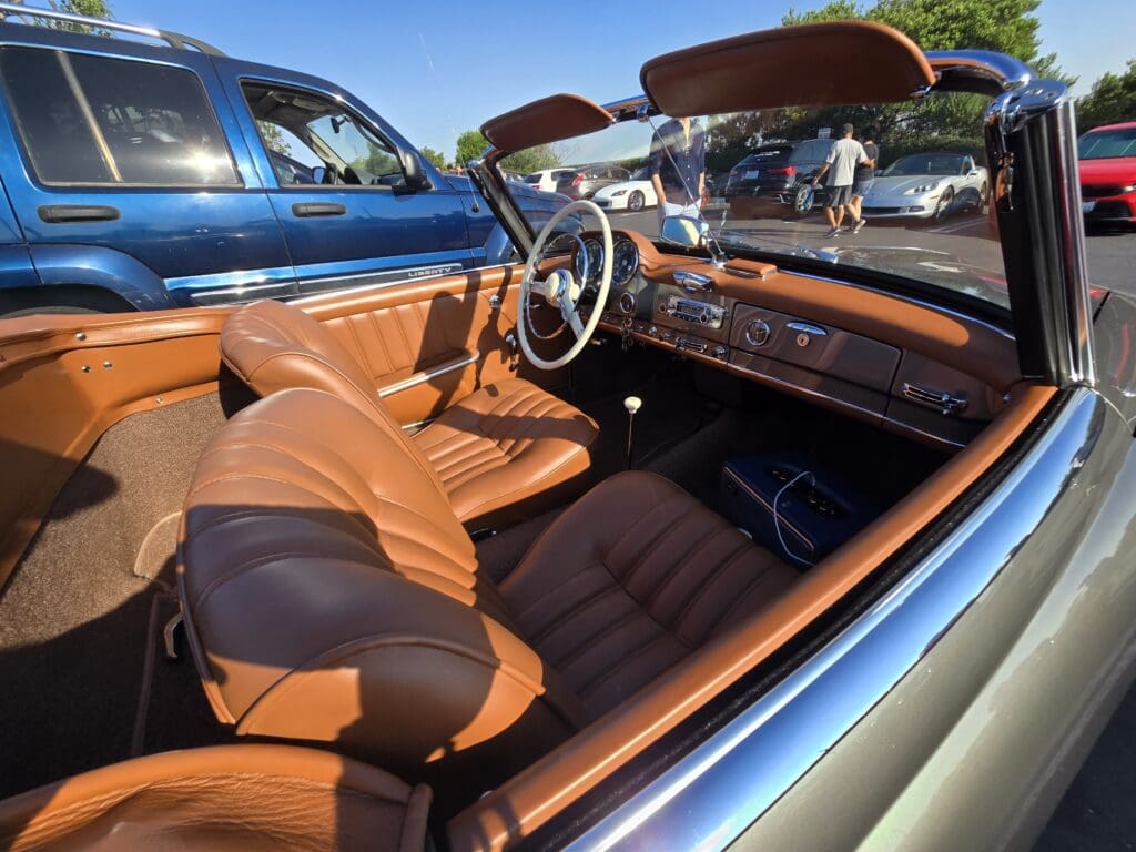 Classic car interior with brown leather seats and wooden dashboard.