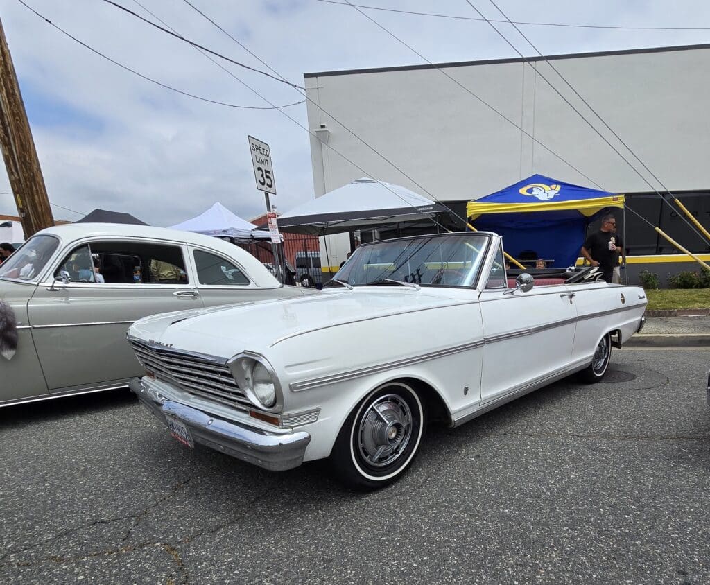 Classic white convertible car parked at an outdoor event.