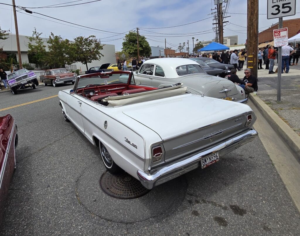 Classic white convertible car displayed at a car show on a sunny day.