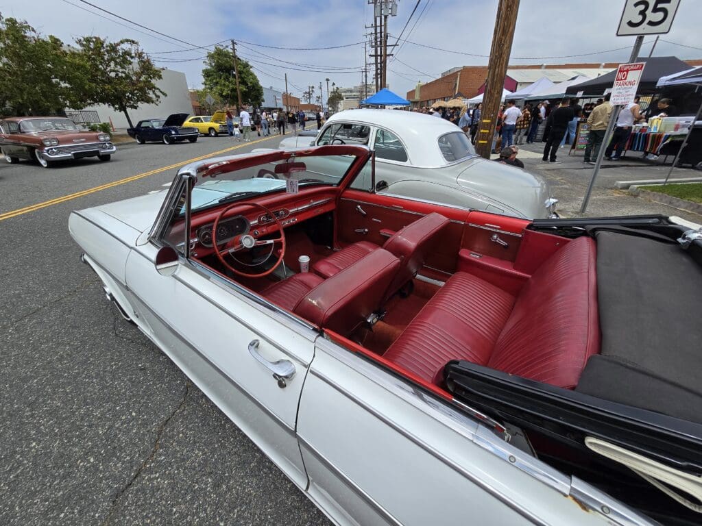 Classic white convertible car with red leather interior parked outdoors.