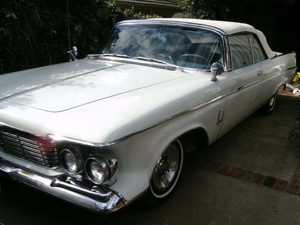 Classic white vintage car parked outdoors.