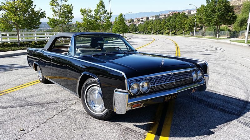 Classic black vintage car parked on a sunny road.