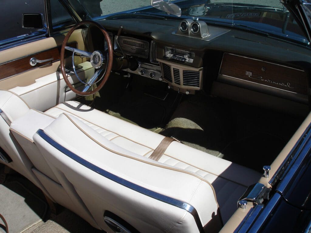 Interior of a classic convertible car with white leather seats.