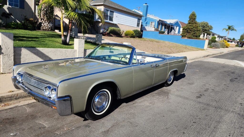 Classic convertible car parked on a sunny suburban street.