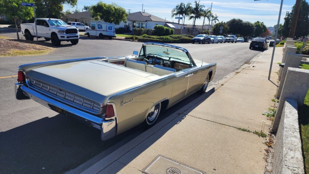 Classic beige convertible car parked on a sunny suburban street.