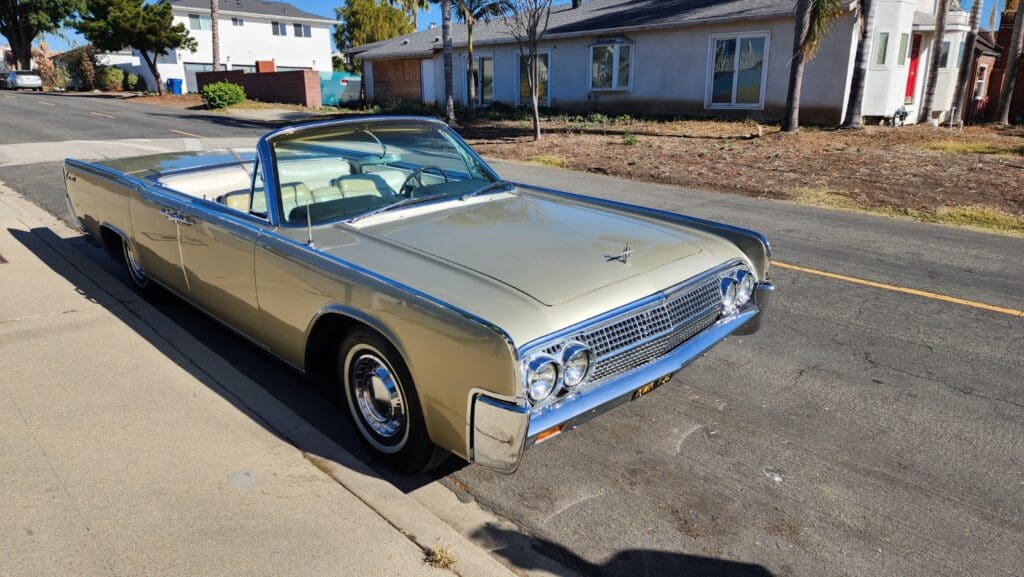 Classic beige convertible parked on a sunny street.