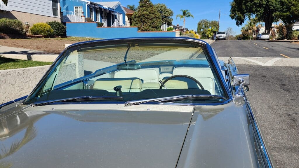 Front view of a white vintage convertible car on a sunny street.
