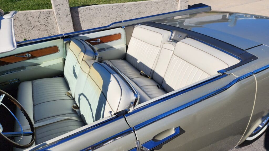 Open convertible car with cream leather seats and blue trim.