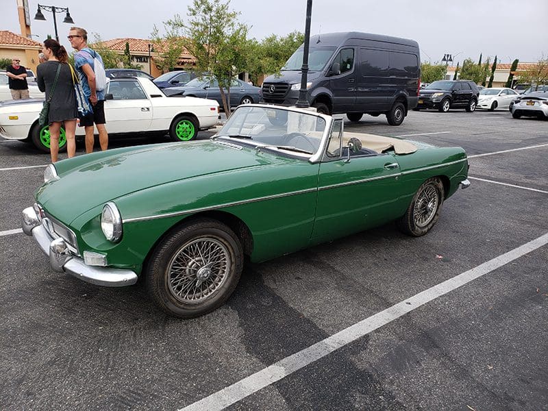Classic green convertible sports car parked outdoors.