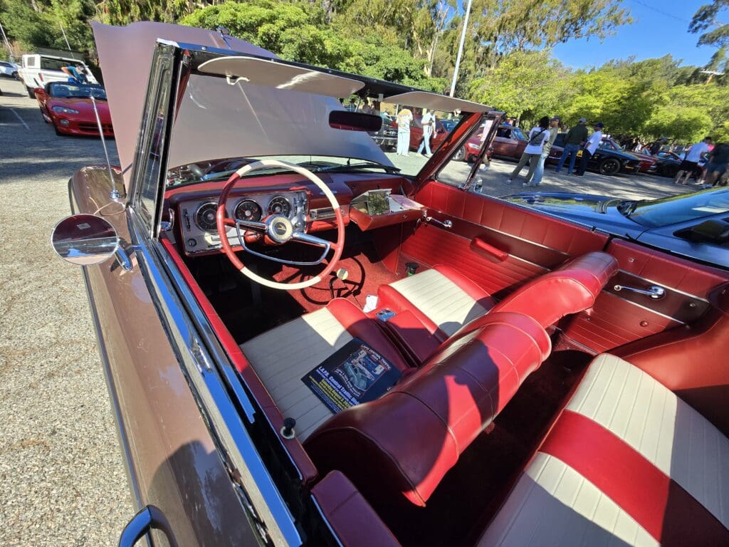 Classic car interior with red and white seats and a red steering wheel.