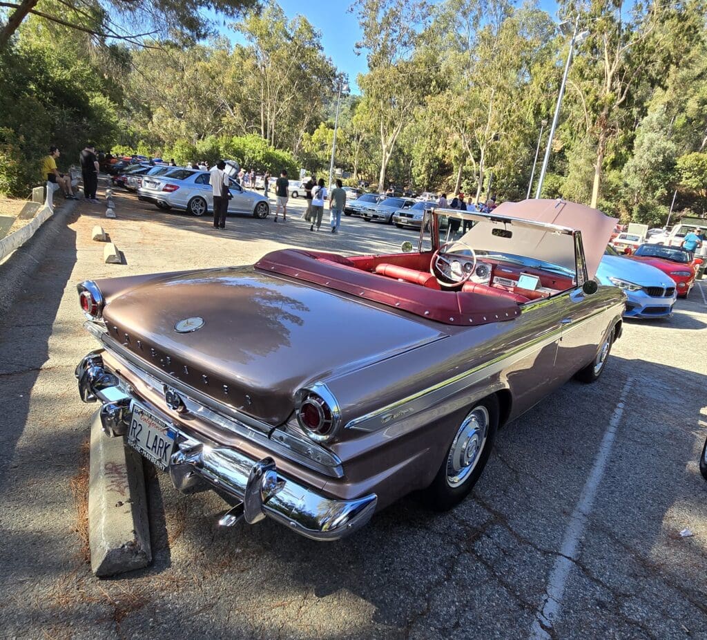 Vintage convertible car with a shiny brown finish parked outdoors.
