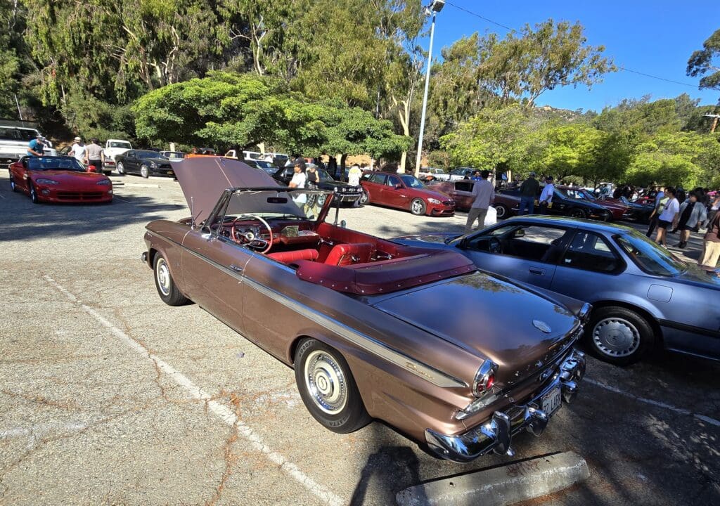Classic brown convertible car with red interior parked outdoors on a sunny day.