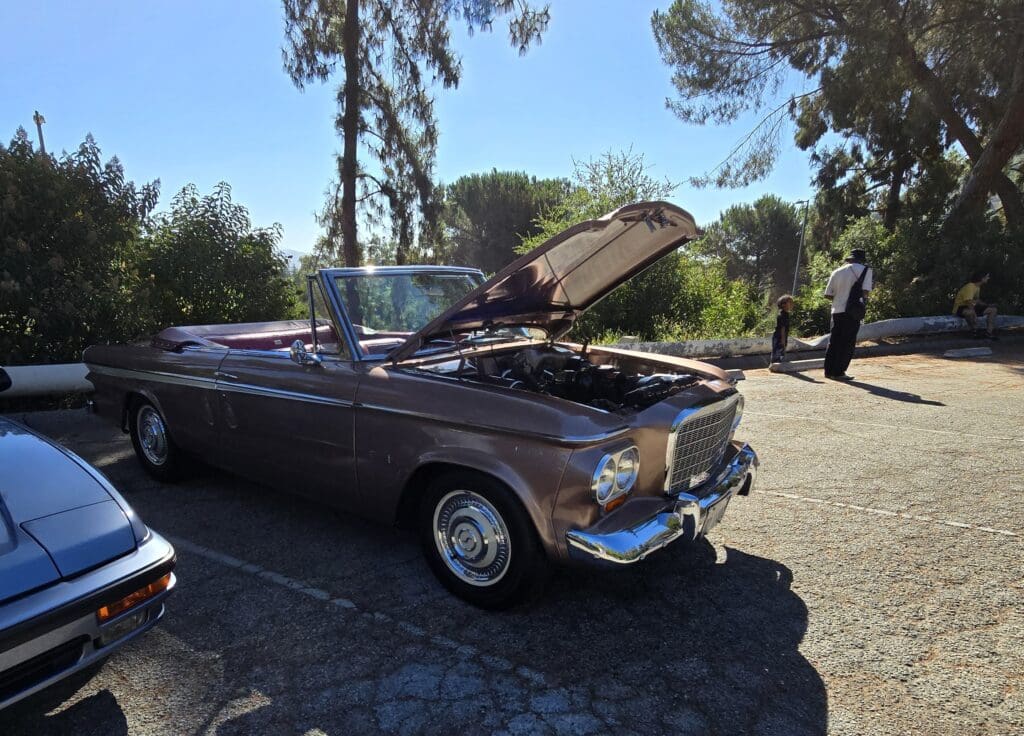 Classic convertible car with its hood open on a sunny day.