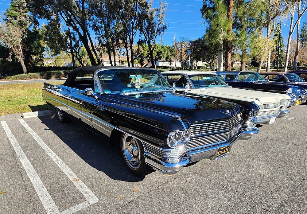 Classic black convertible car parked outdoors on a sunny day.