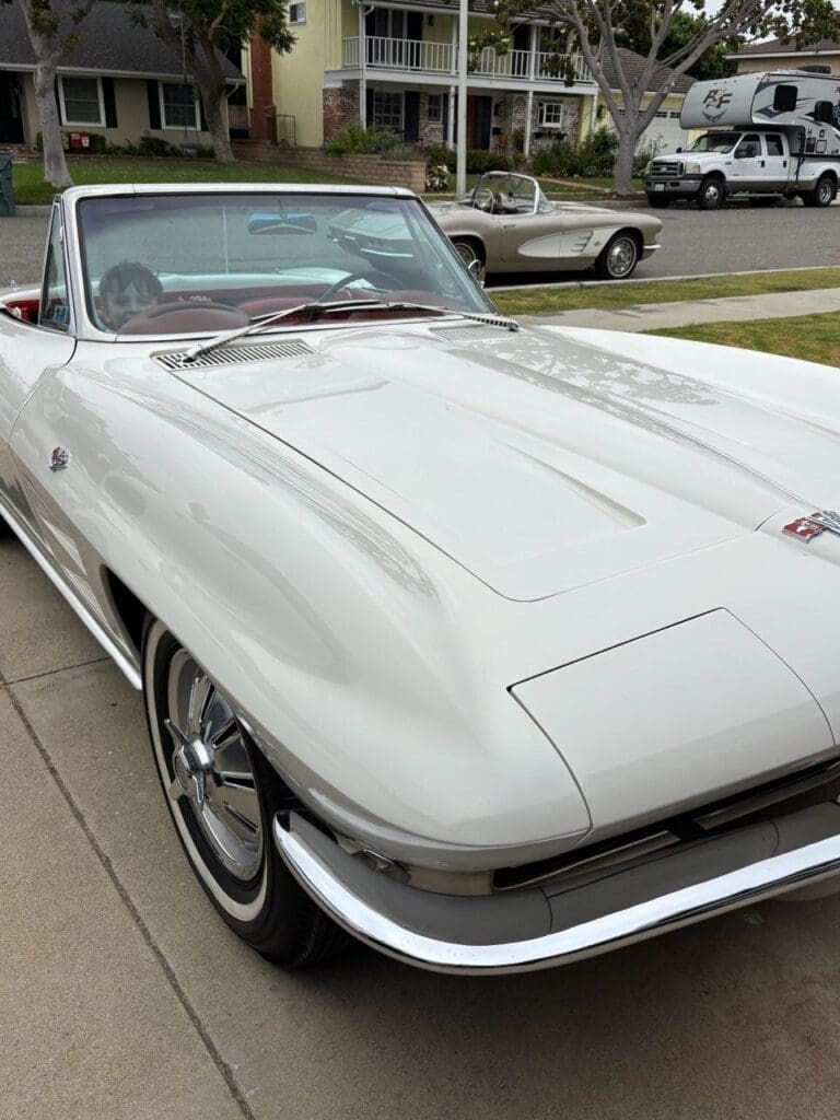 Classic white convertible car parked by the roadside.