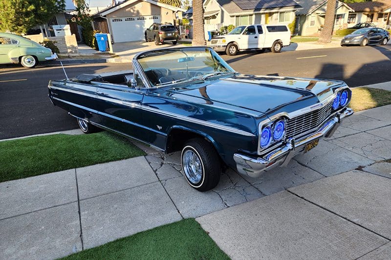 Classic blue convertible car parked on a suburban street.