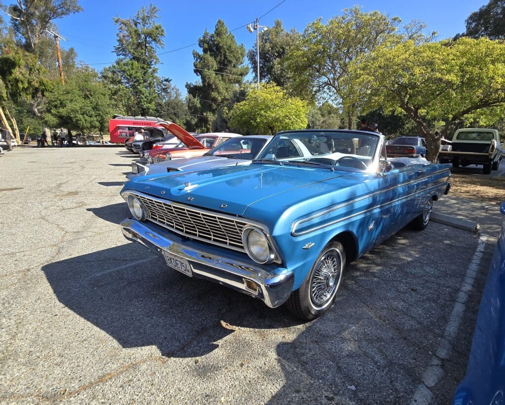 A classic blue convertible car parked under clear skies.