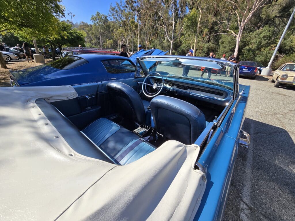 A classic blue convertible car parked under clear skies.
