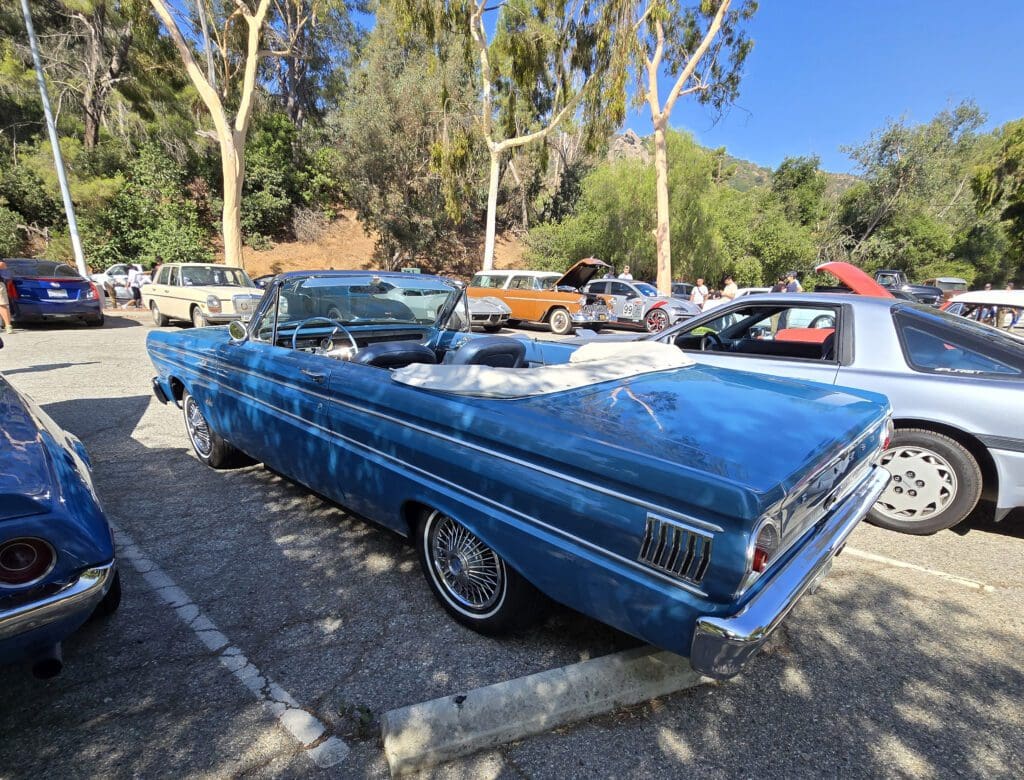 A classic blue convertible car parked outdoors on a sunny day.
