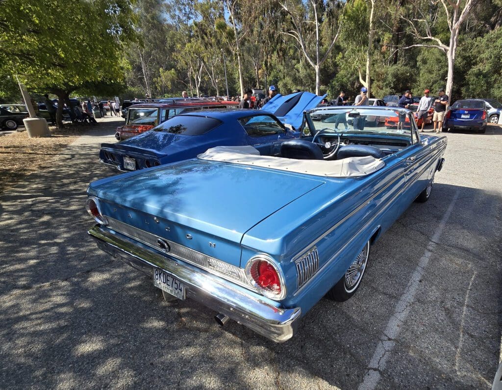 Classic blue convertible car parked at a sunny outdoor car show.