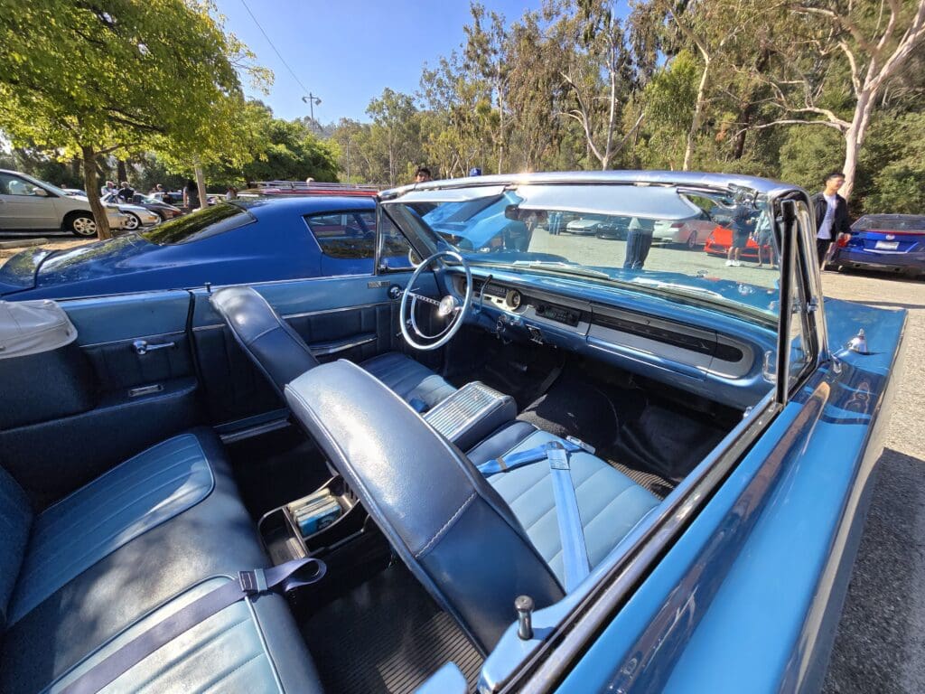 Classic blue convertible car with pristine interior and sunny outdoor setting.