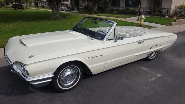 Classic white convertible car parked on a driveway.