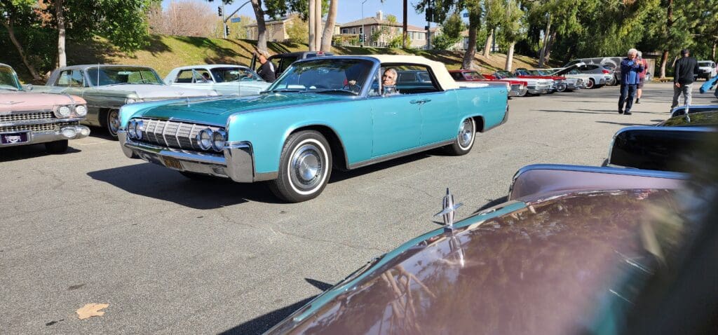 Classic turquoise convertible parked in a sunny lot.