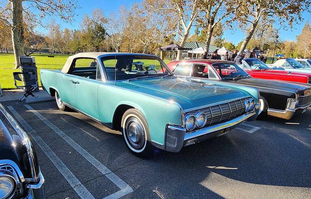 Classic light blue vintage car parked in a lot on a sunny day.