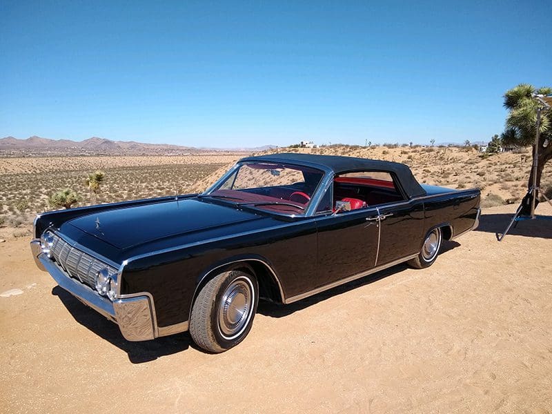 A classic black convertible car parked on a desert road.