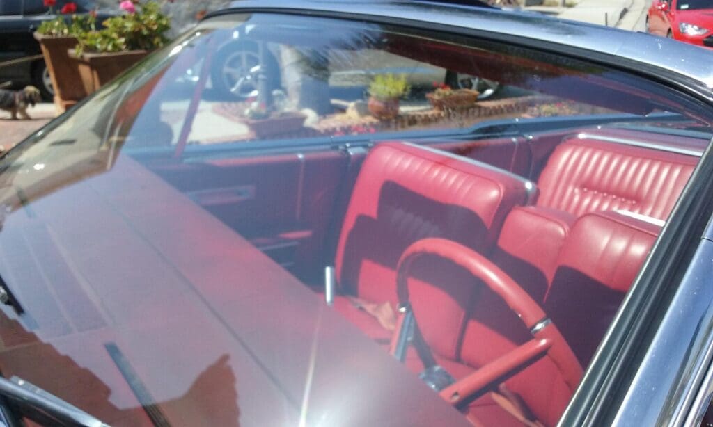 Red leather interior of a vintage car seen through the window.