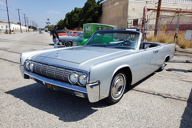 Classic silver convertible car parked outdoors on a sunny day.