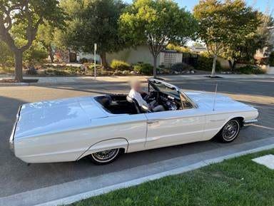 A classic white convertible car parked on a suburban street.
