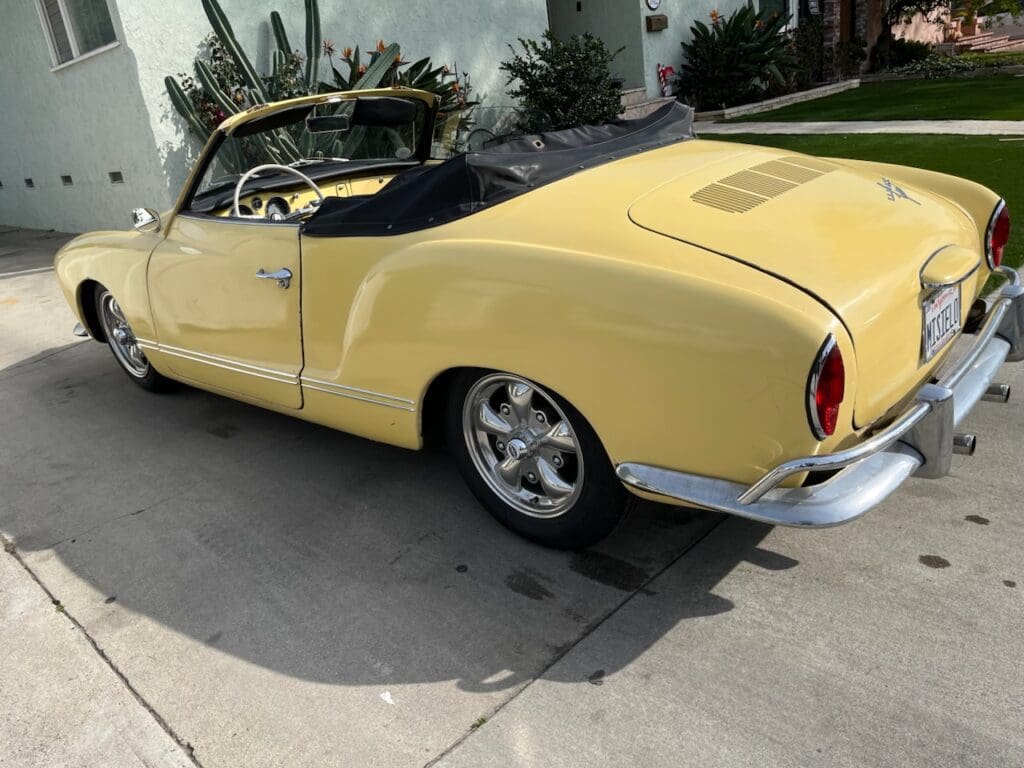 Yellow vintage car parked outside a house.