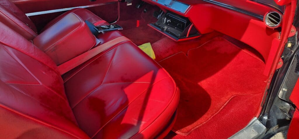 Close-up of a red car interior with leather seats and dashboard.