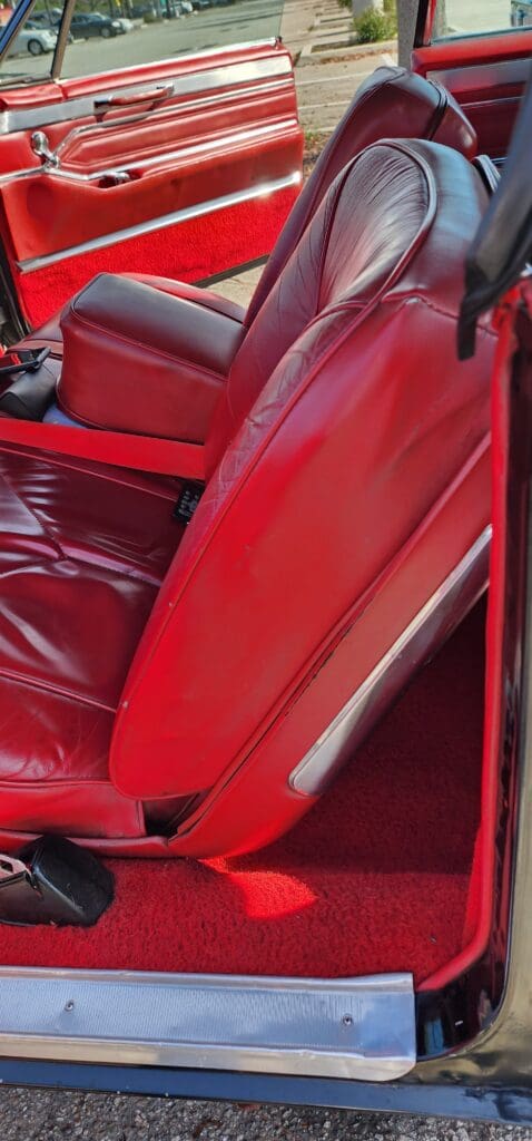 Close-up of a red leather car seat with detailed stitching.