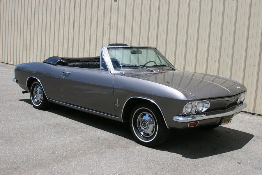 Classic silver convertible car parked outside a beige building.