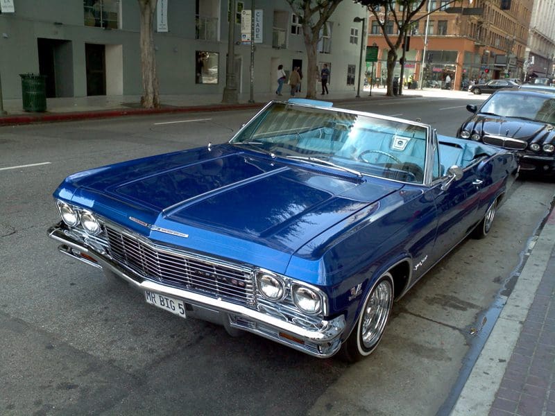 Classic blue convertible car parked on a city street.