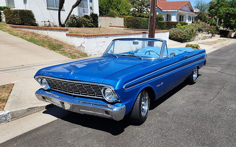 Classic blue convertible car parked on a sunny street.