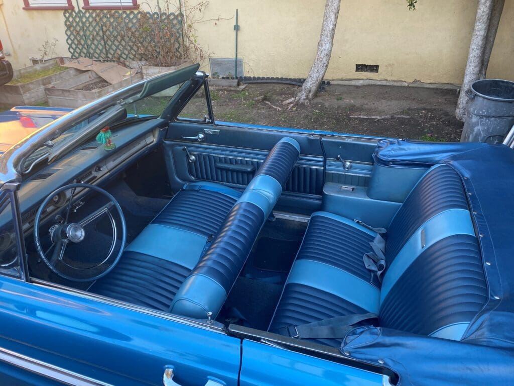 Interior of a classic blue convertible car with blue and black seats.
