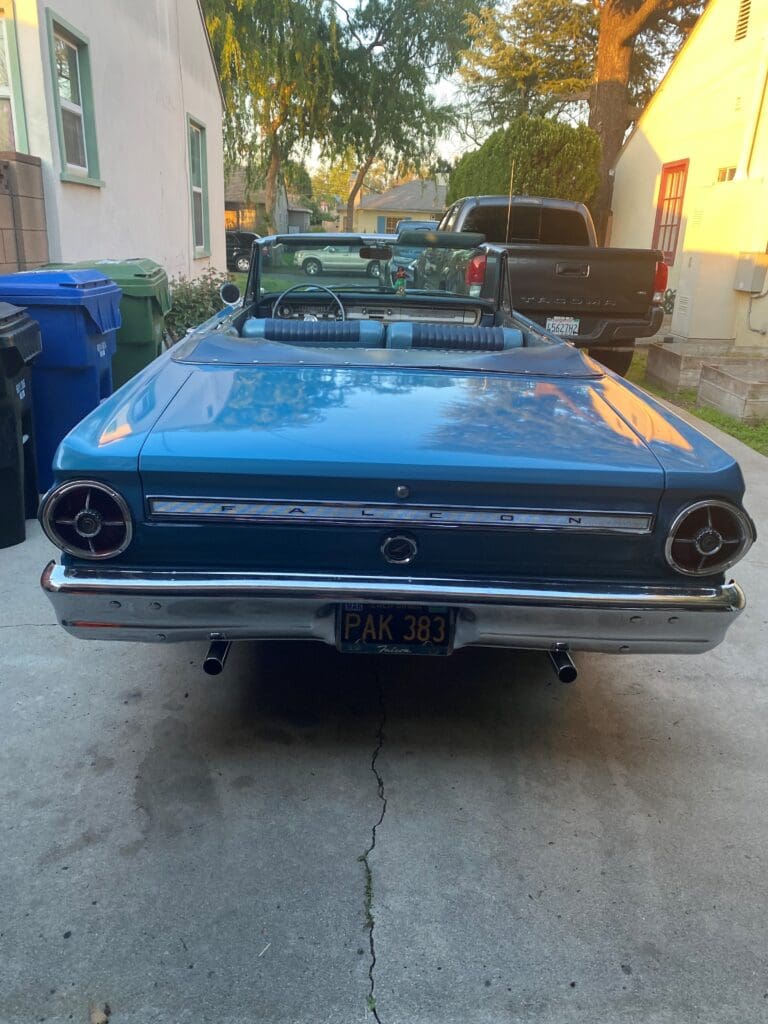 Rear view of a classic blue convertible car parked outdoors.