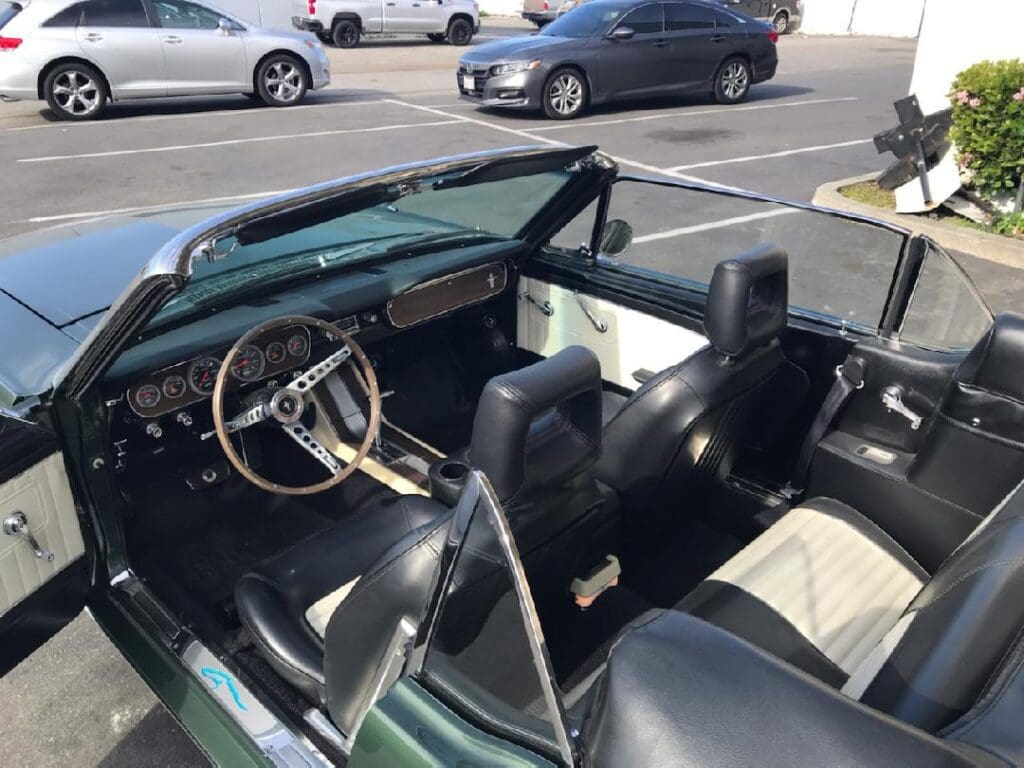 Interior view of a classic convertible car with black seats and a white steering wheel.