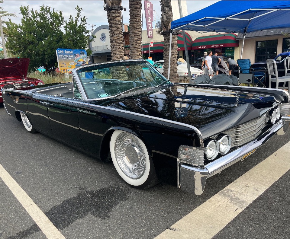 Classic black convertible car parked outdoors with whitewall tires.