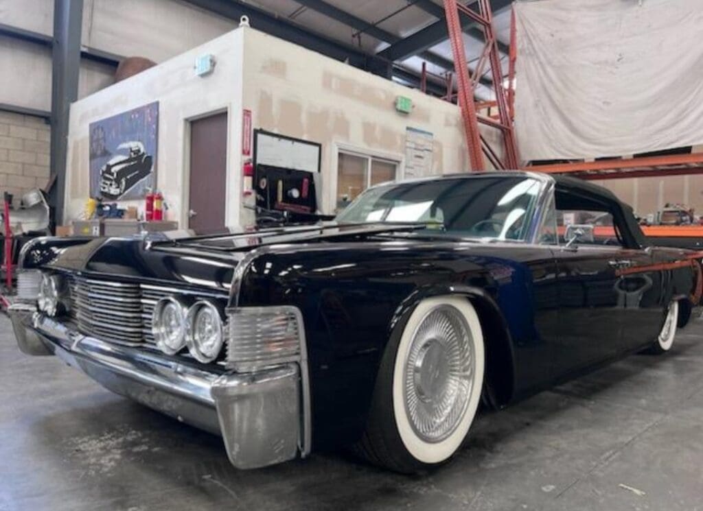 Classic black vintage car with whitewall tires in a garage.