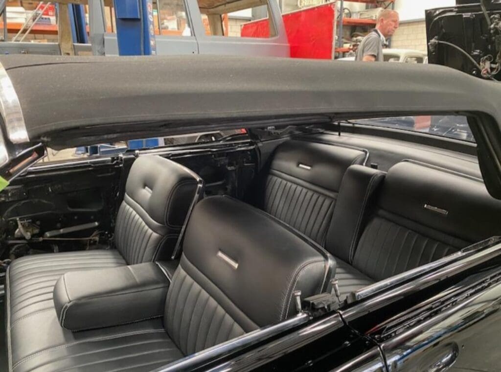 Interior view of a classic car with black leather seats.