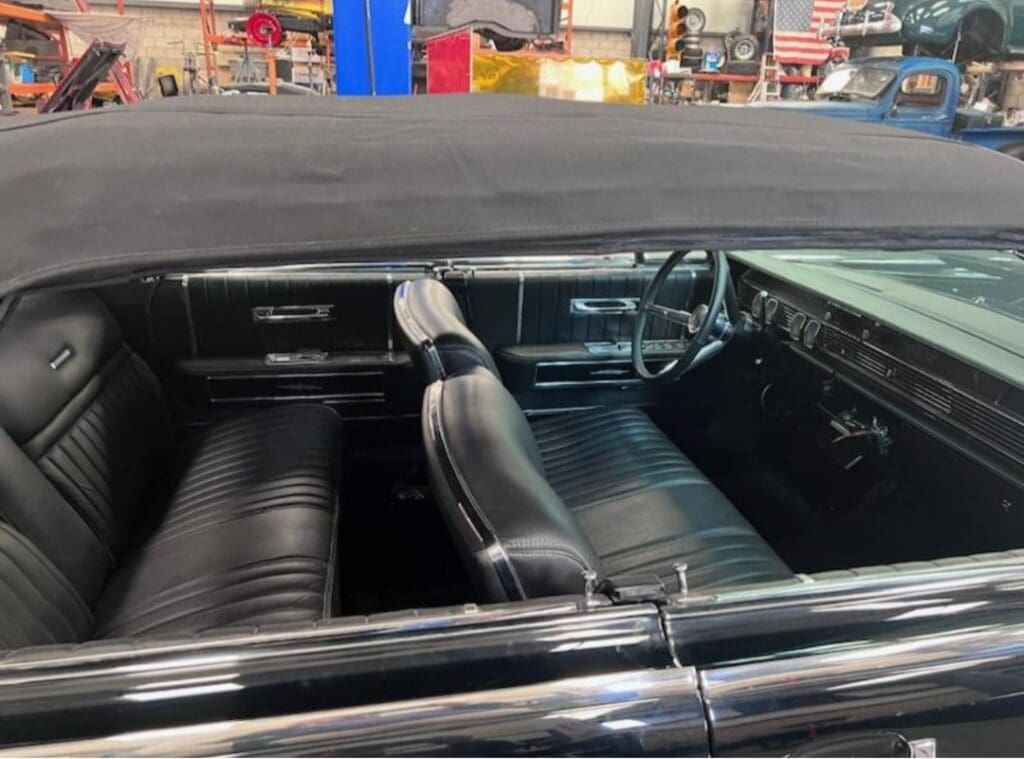 Interior of a vintage car with black leather seats and a classic dashboard.