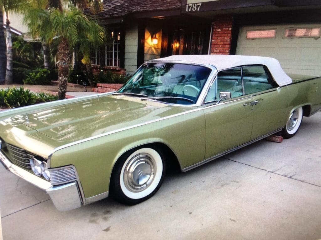 Classic green vintage car parked in front of a house.