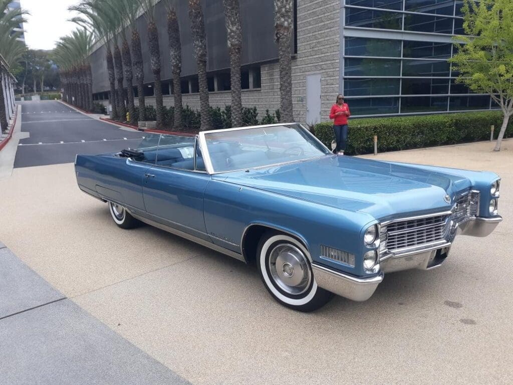 Classic blue convertible car parked beside a modern building.