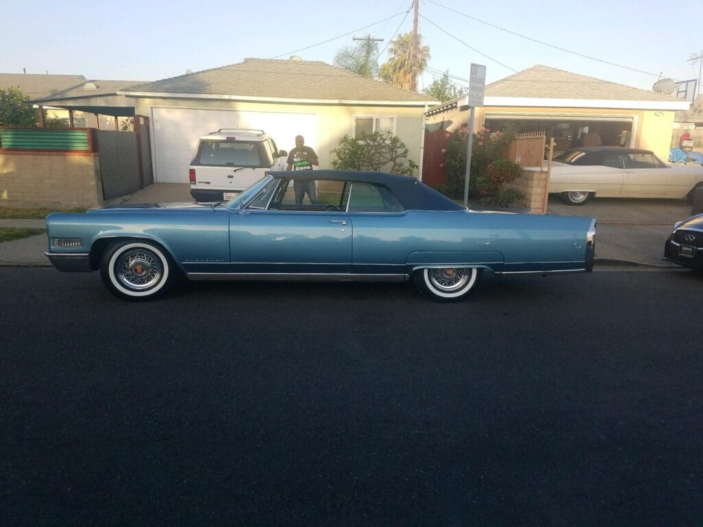 Vintage blue convertible car parked on a suburban street.